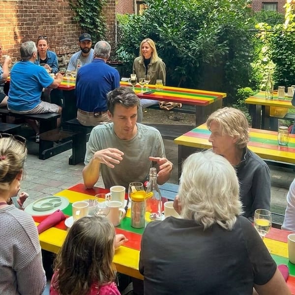 Patrons enjoying a meal at colorful picnic tables in a sunny outdoor restaurant patio.