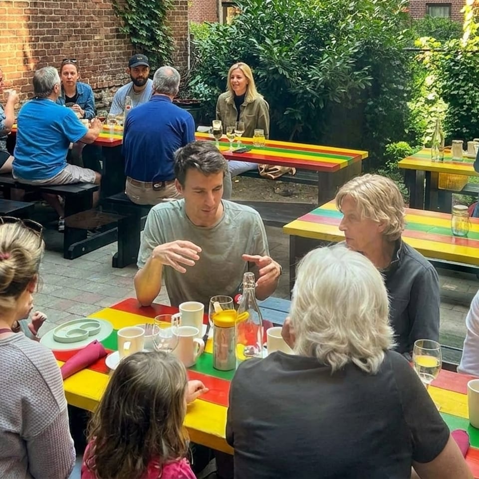 Patrons enjoying a meal at colorful picnic tables in a sunny outdoor restaurant patio.
